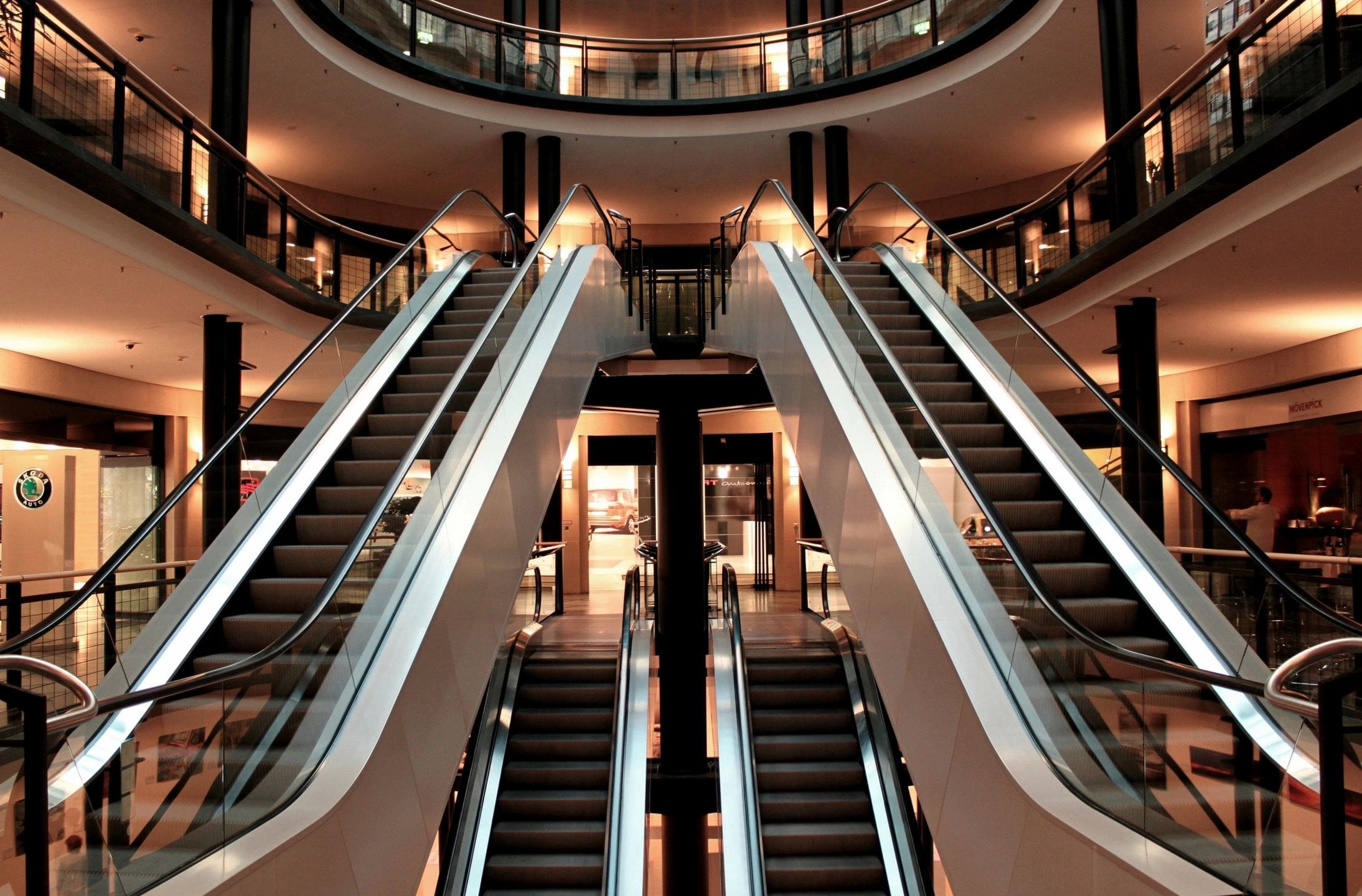 Modern shopping mall escalators with glass railings.